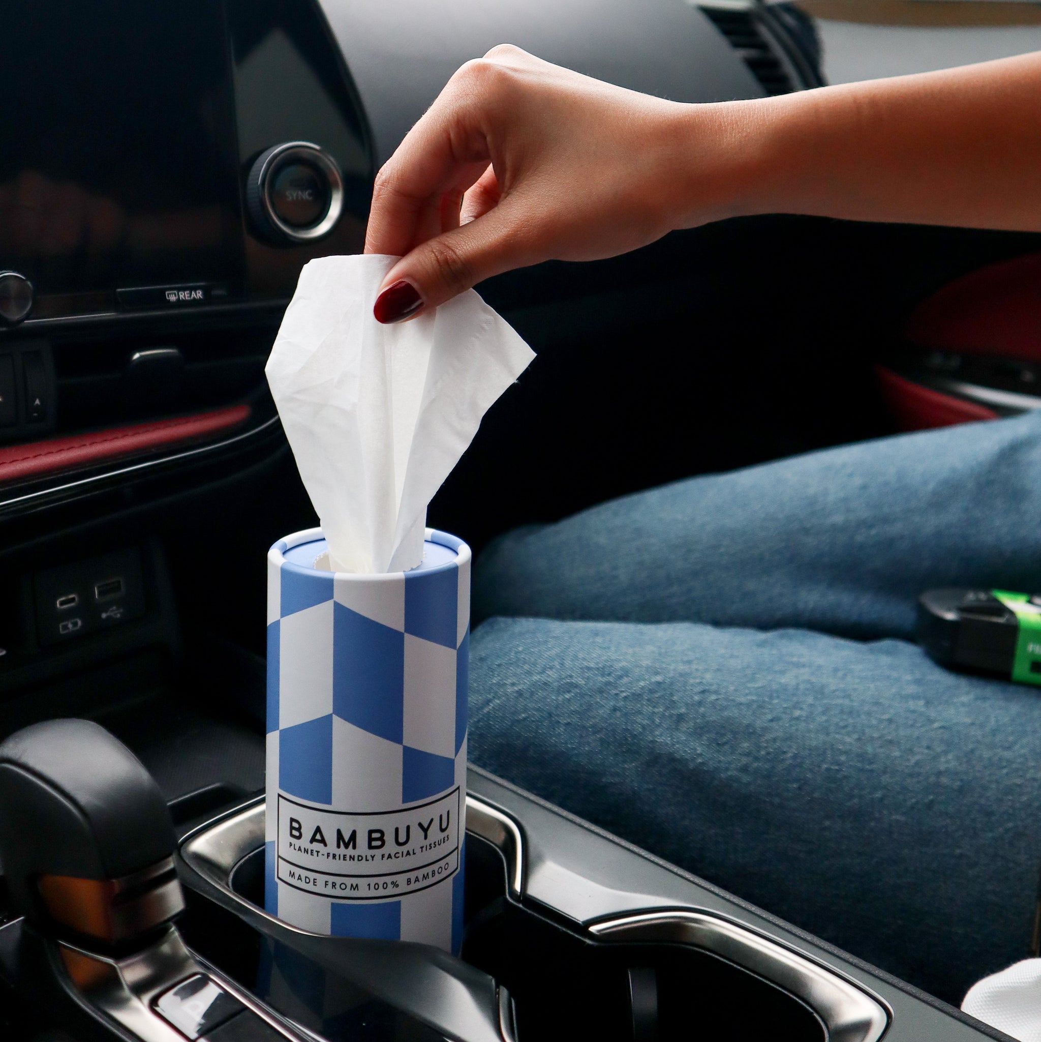Bambuyu bamboo car tissue tube in a car cup holder with a tissue being pulled out